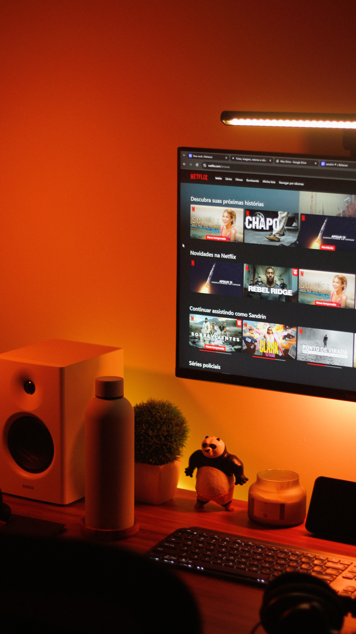 Services Warmly lit home office setup with a computer monitor displaying a streaming service interface.